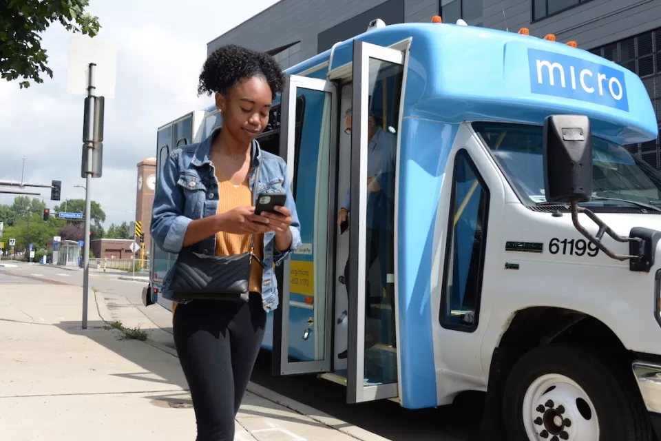 Girl walking in front og blue and white minibus with 'micro' logo in Minneapolis, Minnesota.